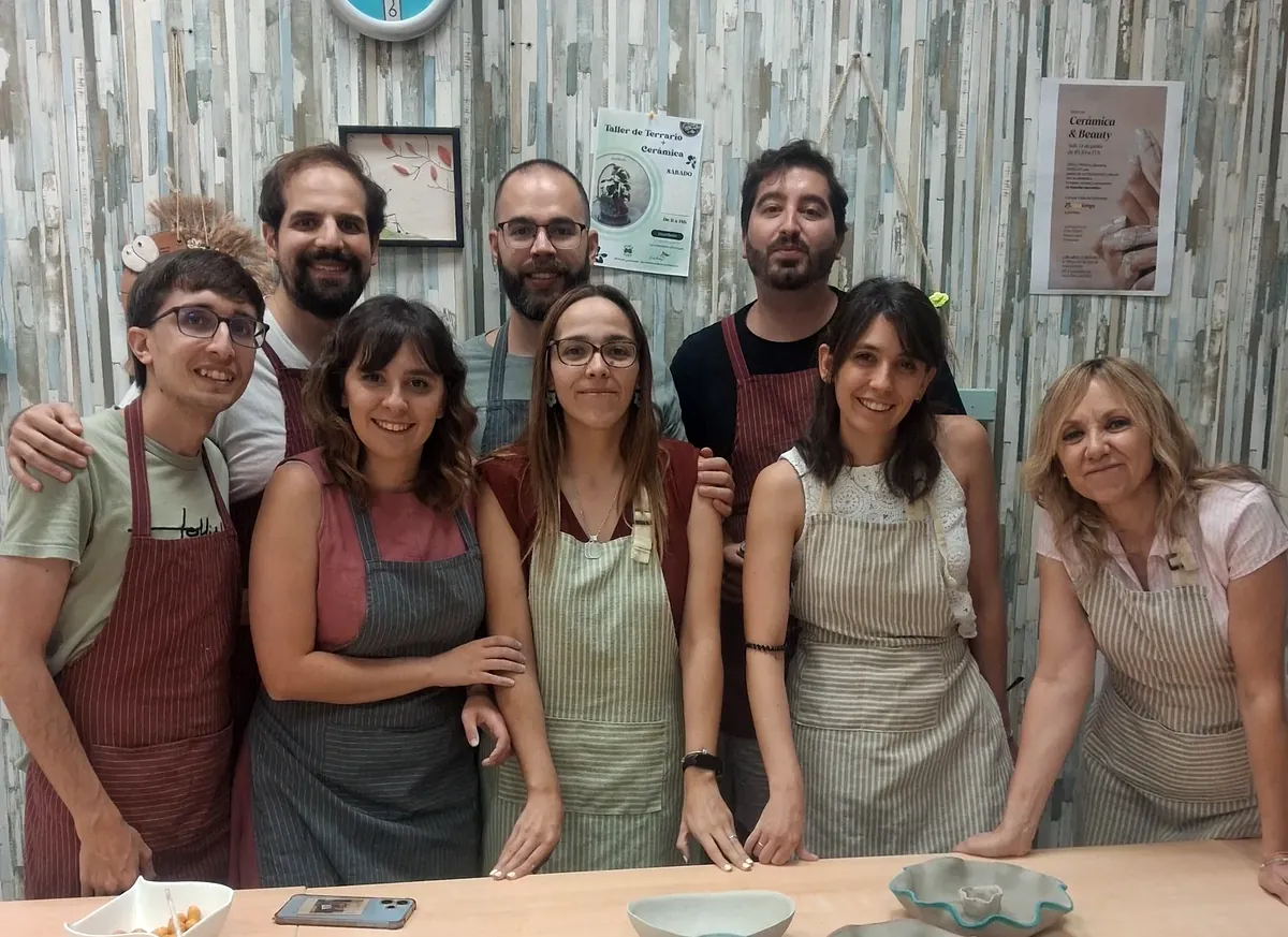 Grupo de amigos posando con delantales tras terminar su primera clase de cerámica en CreArte, con las piezas de barro recién modeladas sobre la mesa del taller en Valladolid