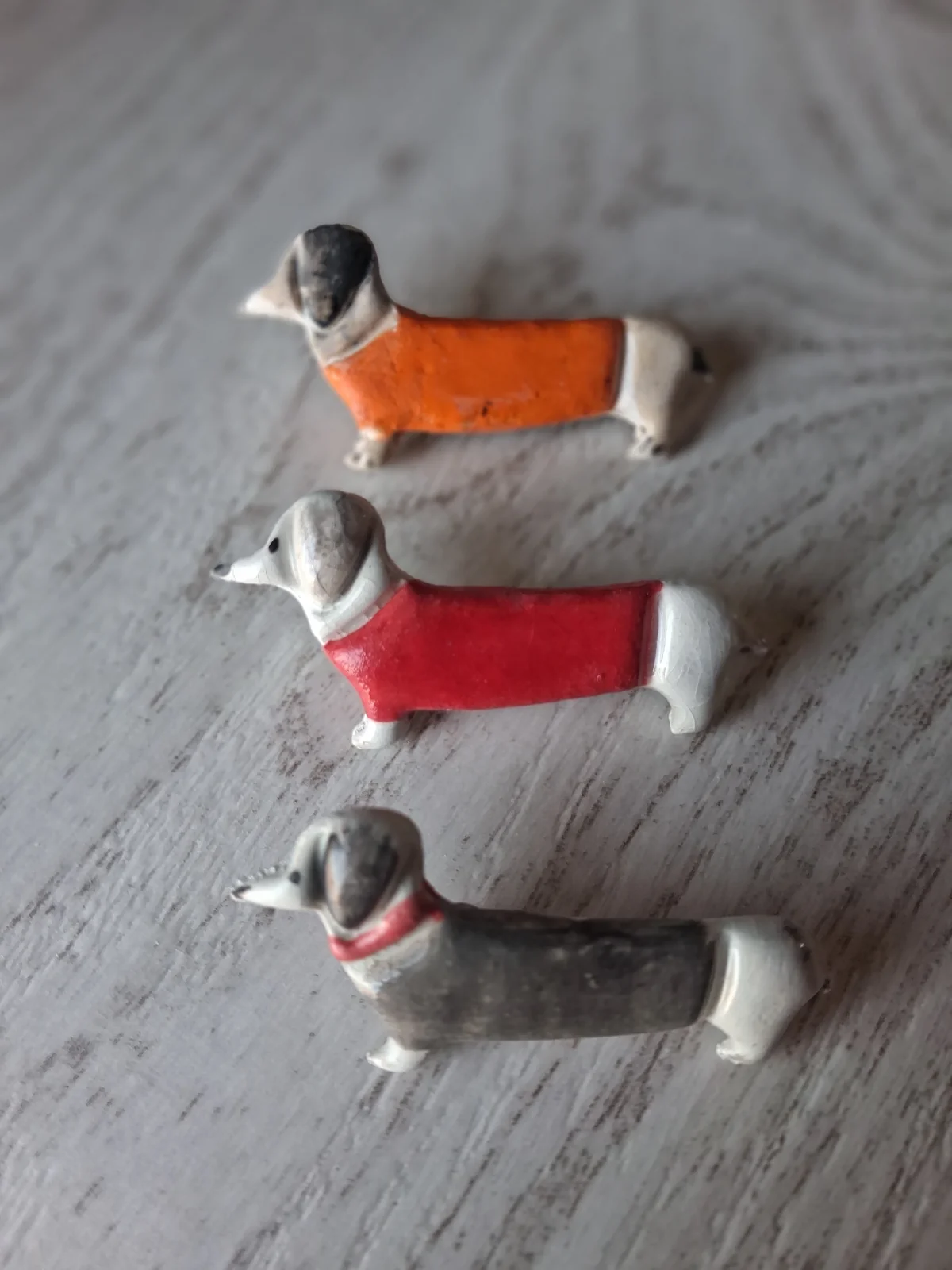 Broches de cerámica con forma de perro salchicha pequeños en naranja, rojo y gris con collar rojo