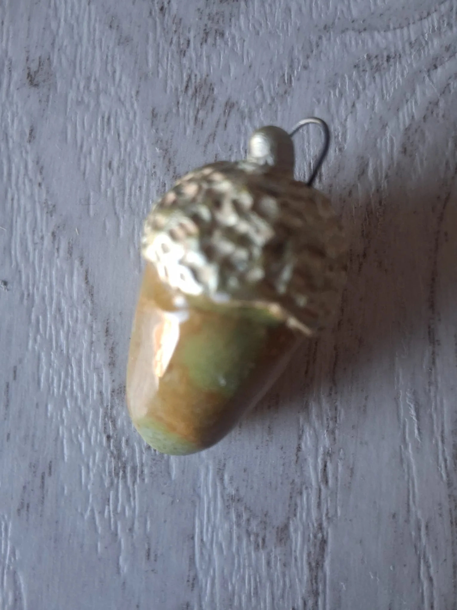 Adorno de Navidad de gres con forma de bellota de unos 4 cm, de cuerpo esmaltado en marrón y verde y capuchón crema verdoso en relieve, con anilla de alambre para colgar, esmaltado a mano en Valladolid — CreArte