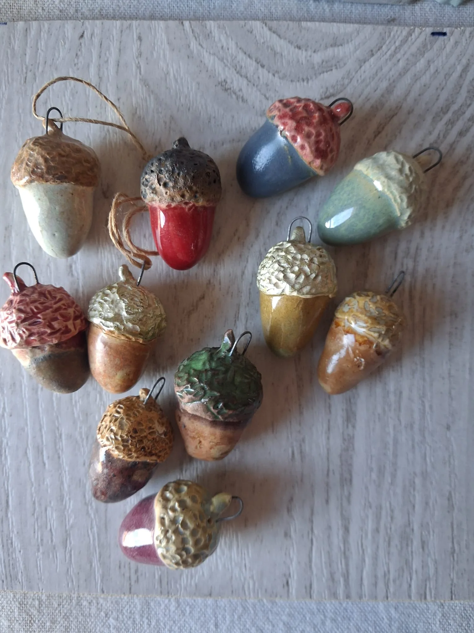 Bellotas de Navidad de cerámica de gres, de unos 4 cm, esmaltadas a mano en rojo, azul, verde menta, morado, marrón y ocre, con capuchón en relieve y anilla de alambre para colgar en el árbol, hechas en Valladolid — CreArte