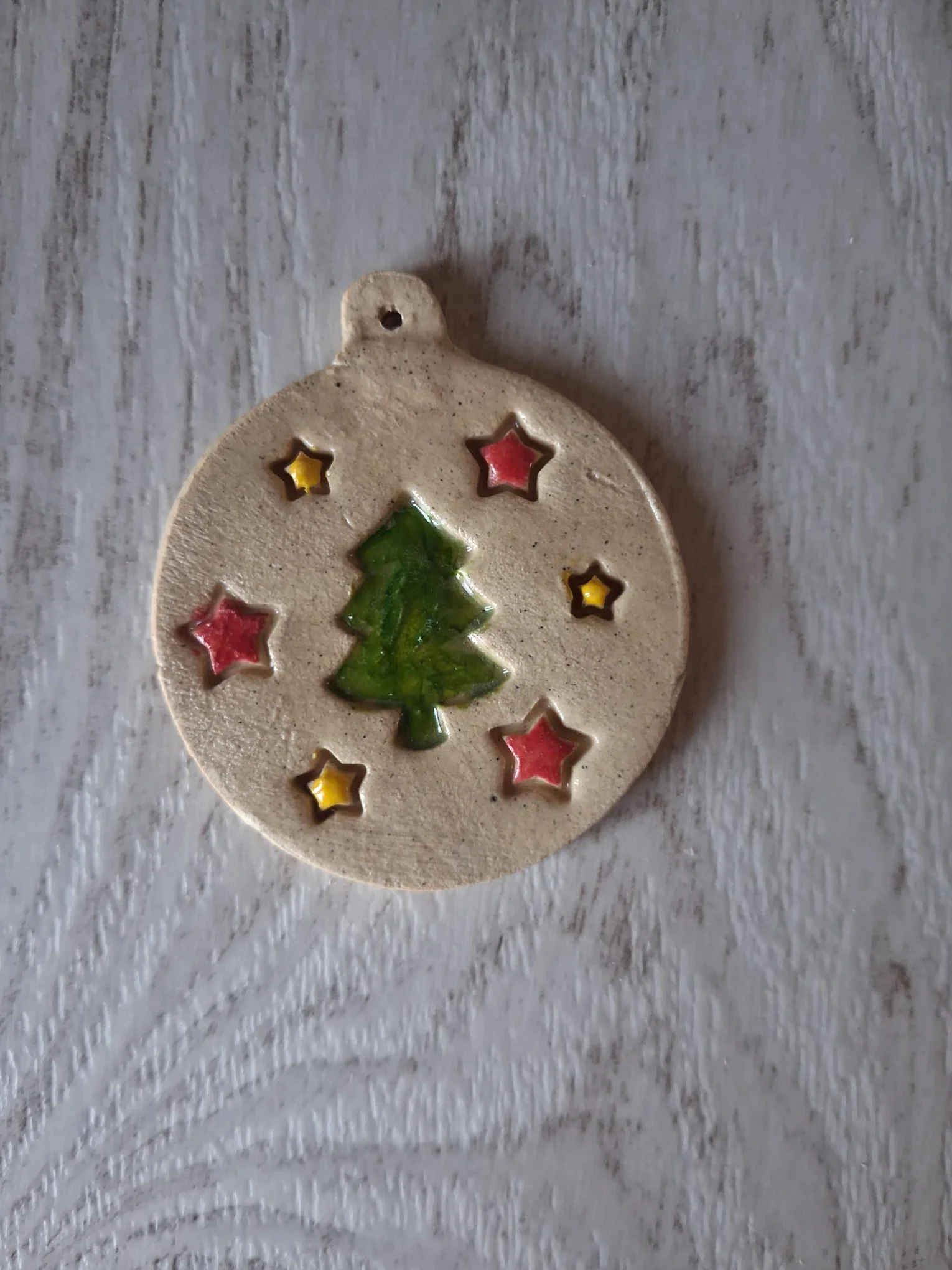 Bola de Navidad de cerámica con un abeto verde esmaltado rodeado de estrellas rojas y amarillas, de unos 4,5 cm, adorno artesanal para el árbol hecho a mano en Valladolid — CreArte