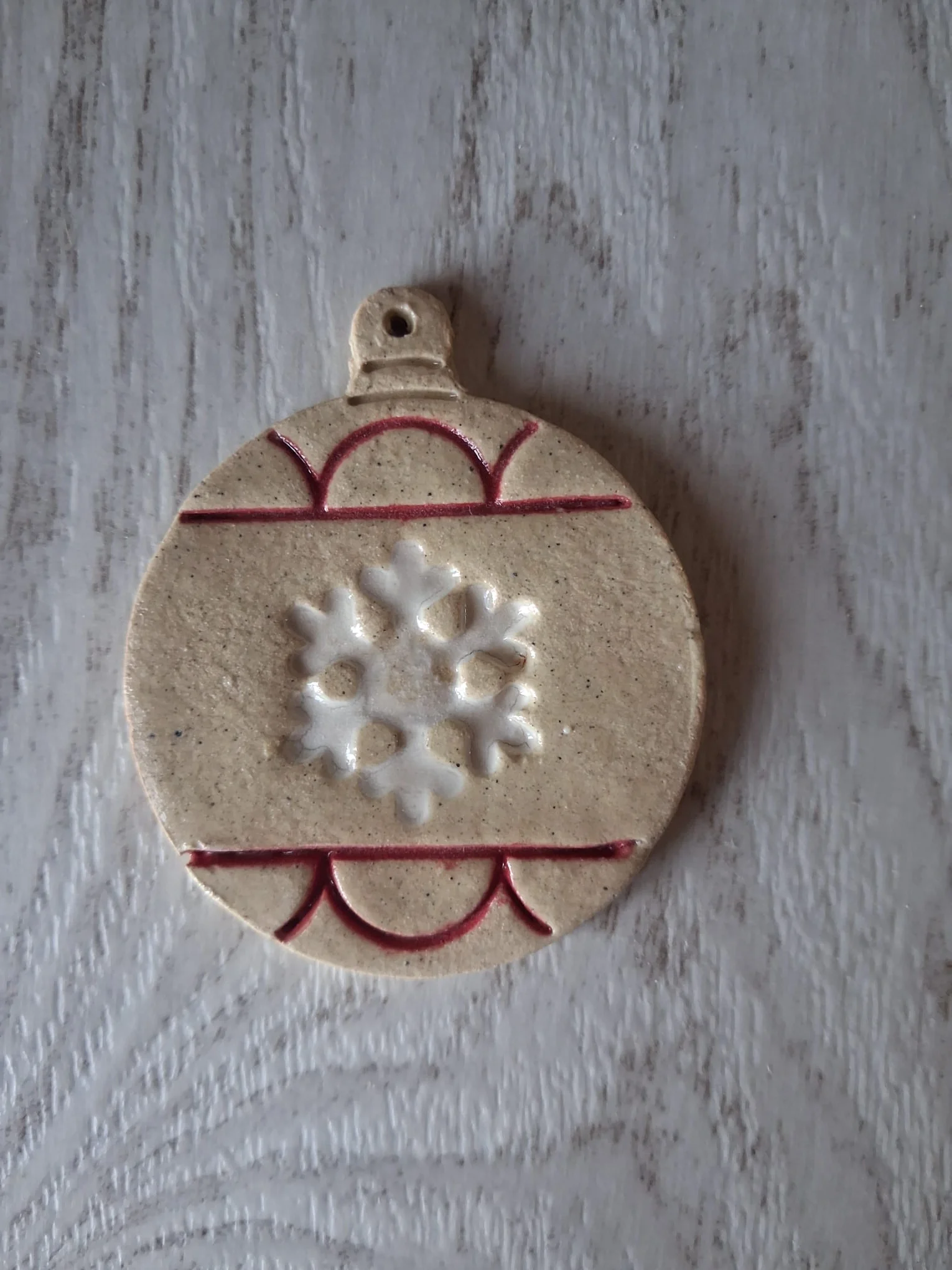 Bola de Navidad de cerámica con un copo de nieve blanco esmaltado en el centro y líneas rojas decorativas, adorno artesanal para el árbol hecho a mano en Valladolid — CreArte