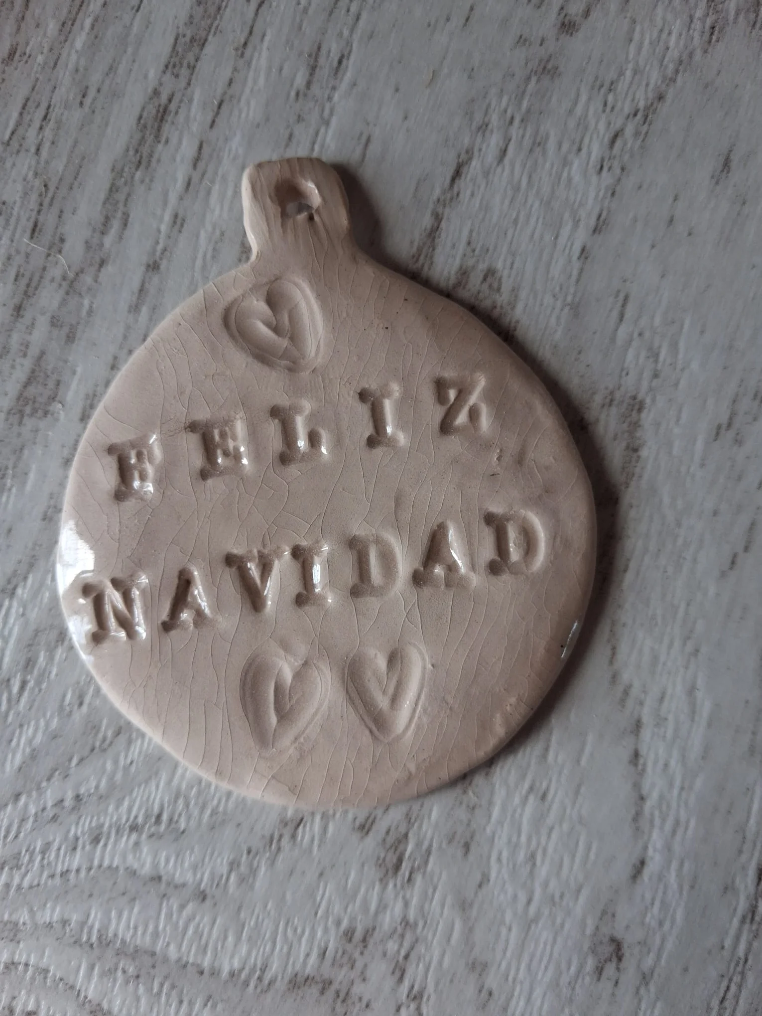 Bola de Navidad de cerámica con el mensaje Feliz Navidad en relieve y tres corazones, esmalte craquelado, de unos 4,5 cm, adorno artesanal hecho a mano en Valladolid — CreArte