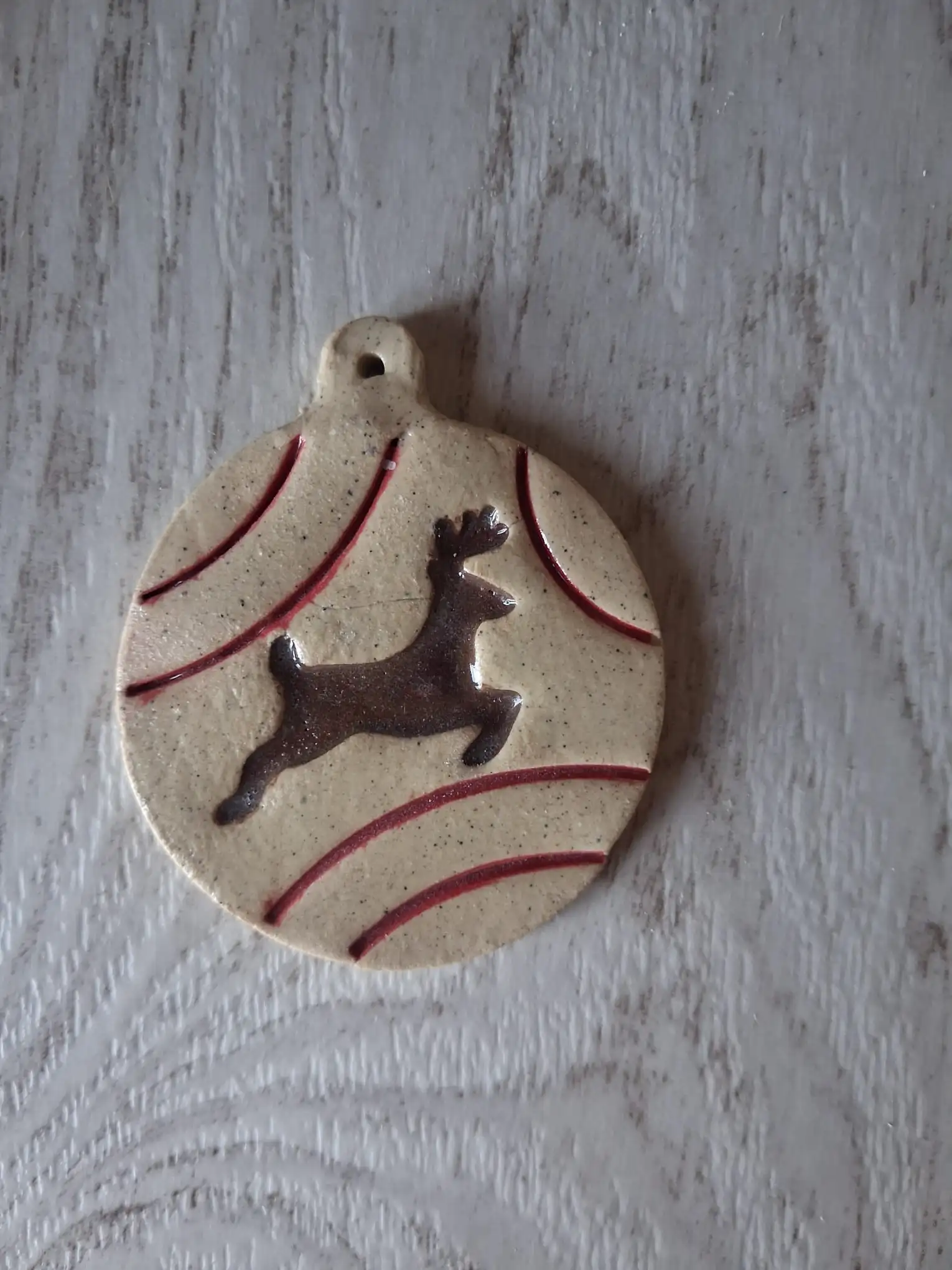 Bola de Navidad de cerámica con reno saltando en esmalte marrón y líneas rojas, adorno artesanal para el árbol hecho a mano en Valladolid — CreArte