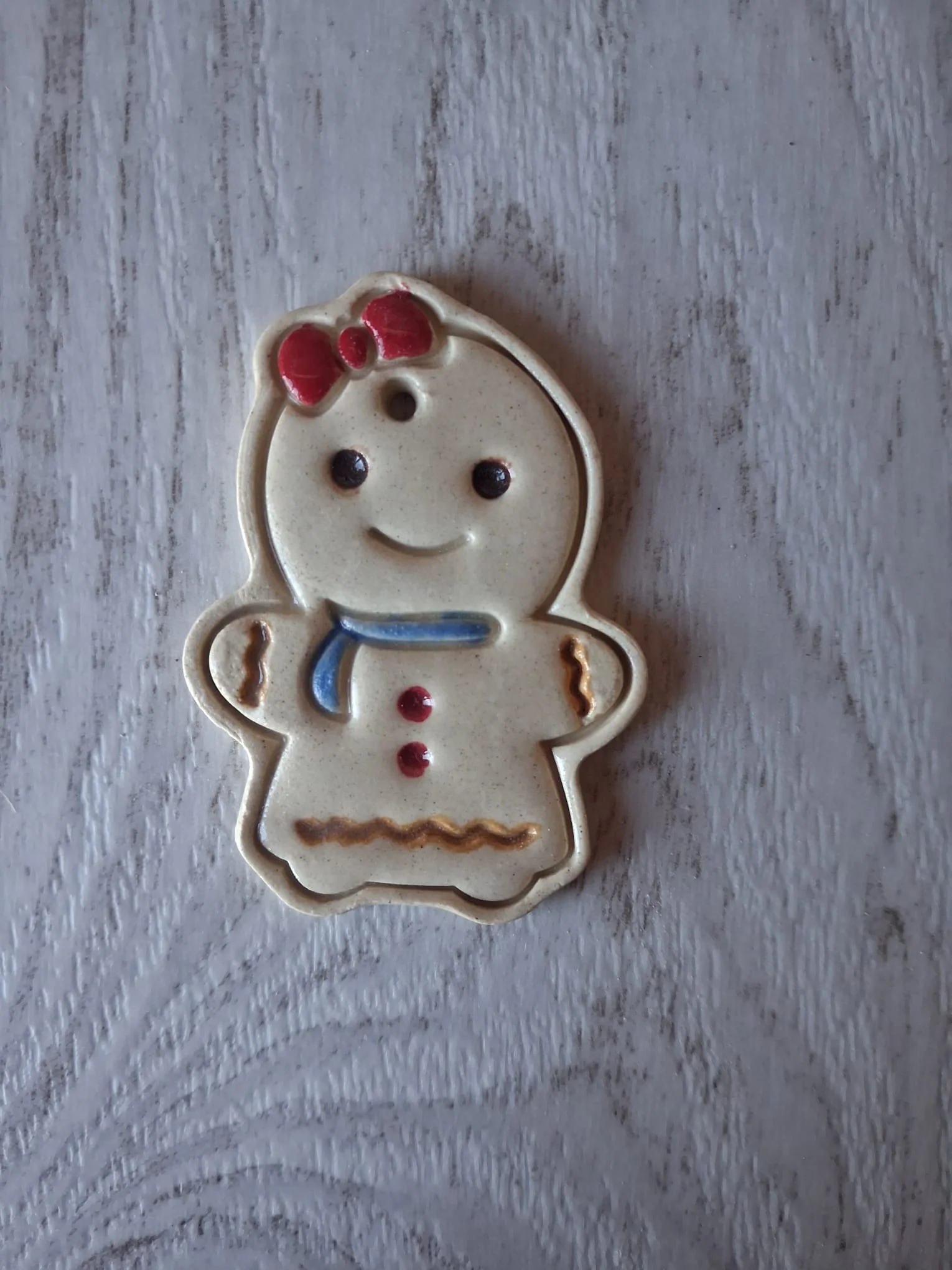 Adorno de Navidad de cerámica con forma de galleta de jengibre niña con lazo rojo, bufanda azul y botones rojos, esmaltado a mano en Valladolid — CreArte