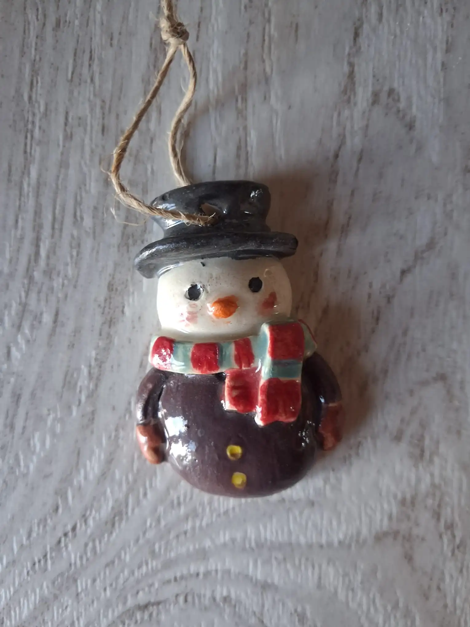Adorno de Navidad de cerámica con muñeco de nieve de sombrero negro, bufanda roja y azul claro y botones amarillos, con cordel de yute, esmaltado a mano en Valladolid — CreArte
