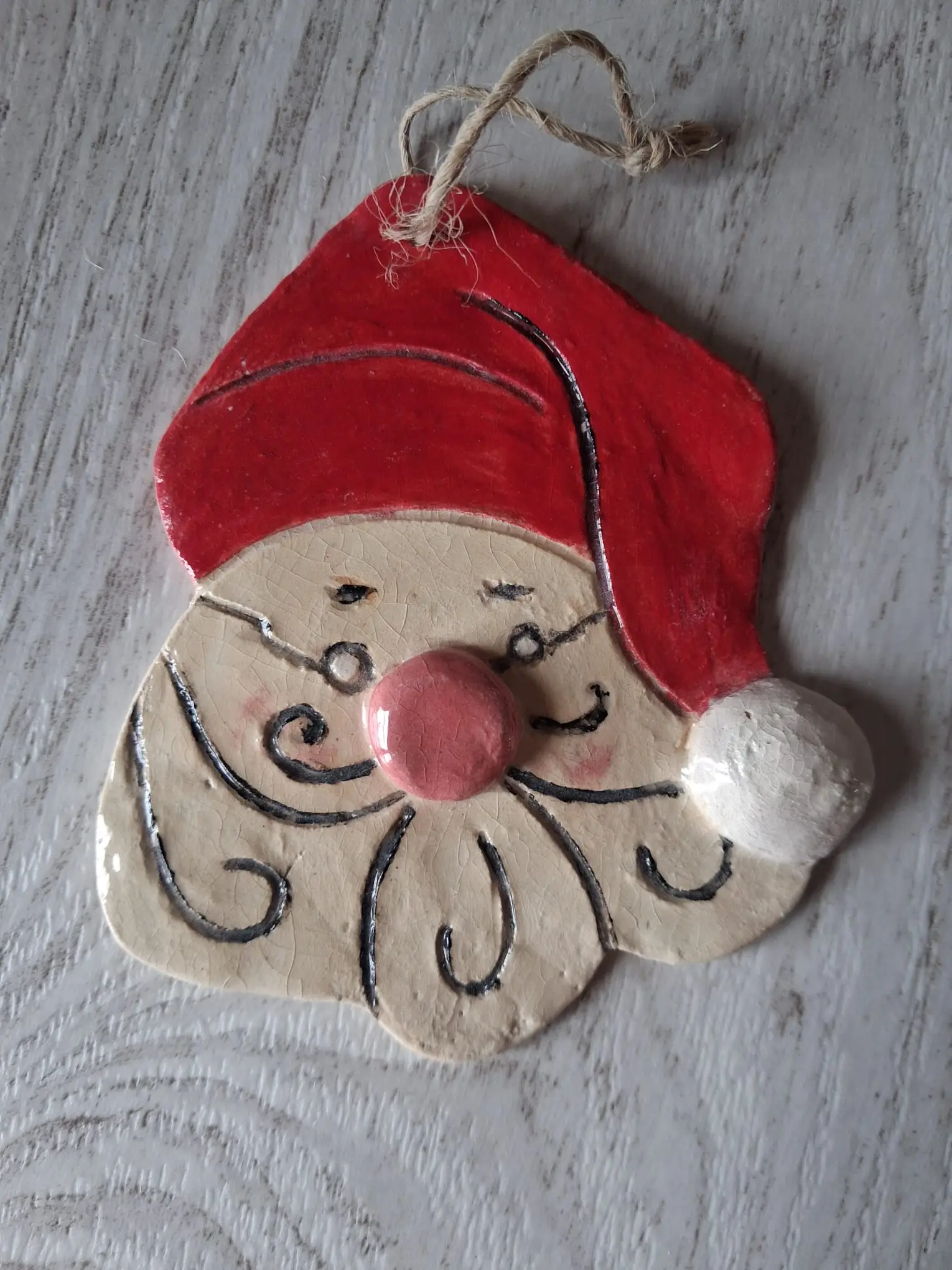 Adorno de Navidad de cerámica con cara de Papá Noel, gorro rojo con pompón blanco, nariz rosa y barba con rizos negros, con cordel de yute, hecho a mano en Valladolid — CreArte