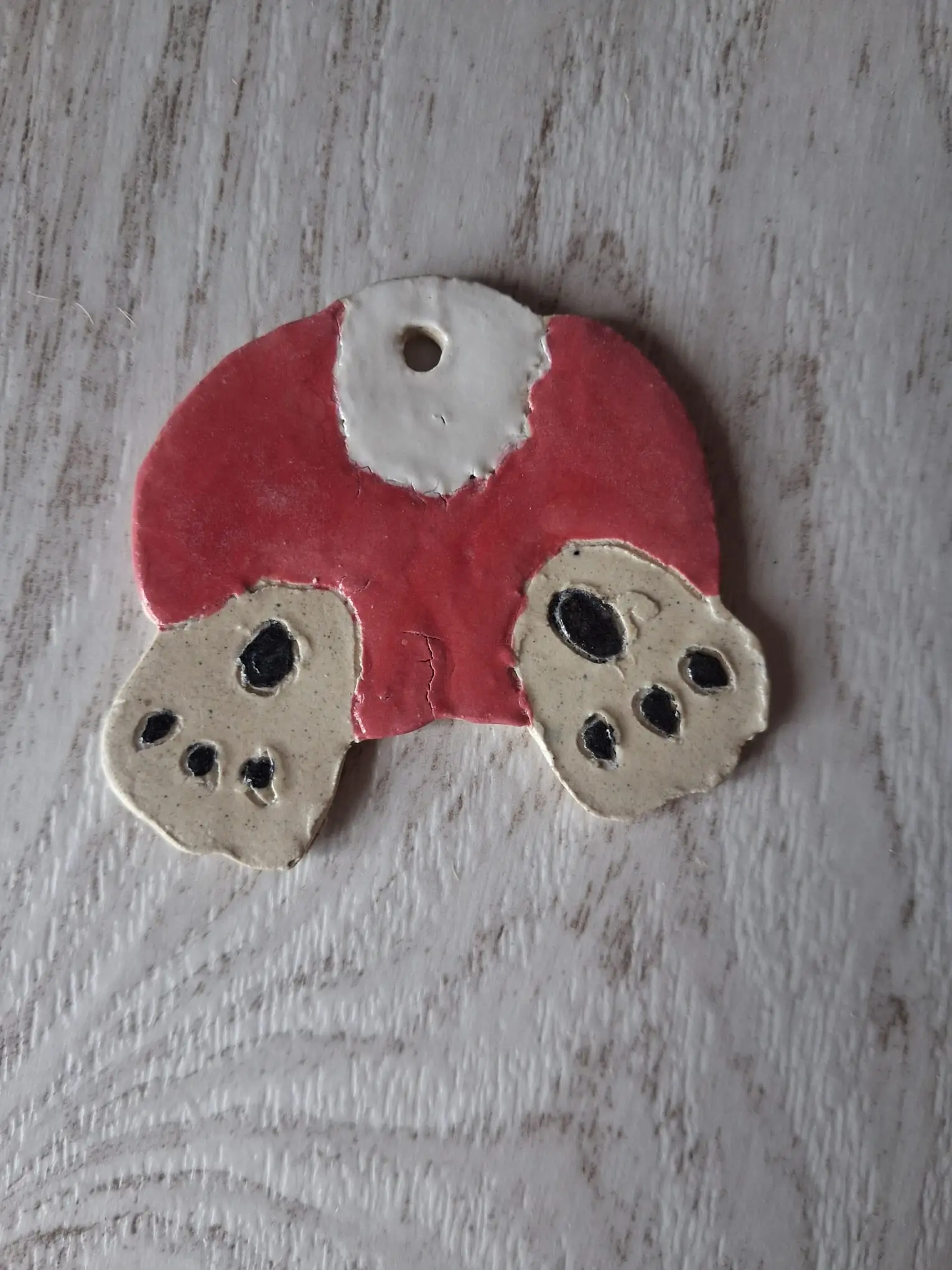 Adorno de Navidad de cerámica con un conejo metiéndose en un agujero, con el cuerpo rojo y las patas traseras beige con almohadillas negras al aire, hecho a mano en Valladolid — CreArte