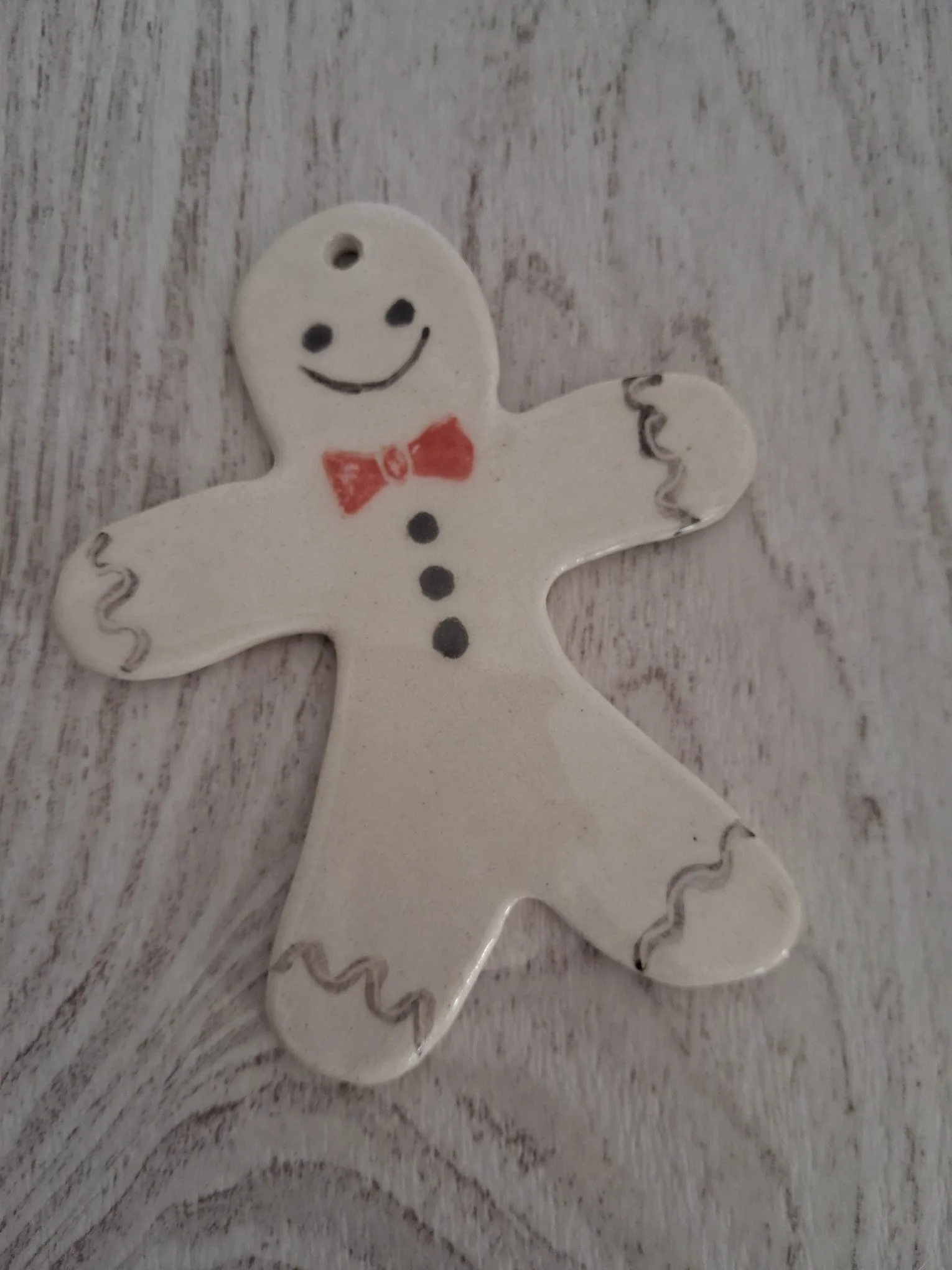 Adorno de Navidad de cerámica con galleta de jengibre blanca, pajarita roja, botones negros y detalles grises, personalizable, pintado a mano en Valladolid — CreArte