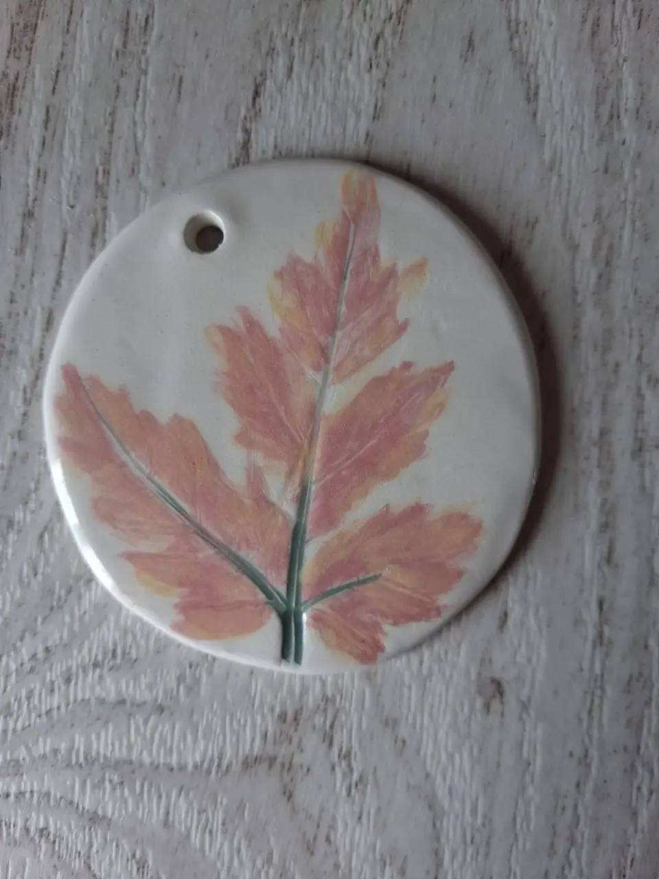 Adorno de cerámica redondo blanco con una hoja estampada en tonos rosa y naranja con tallo verde, personalizable, hecho a mano en Valladolid — CreArte