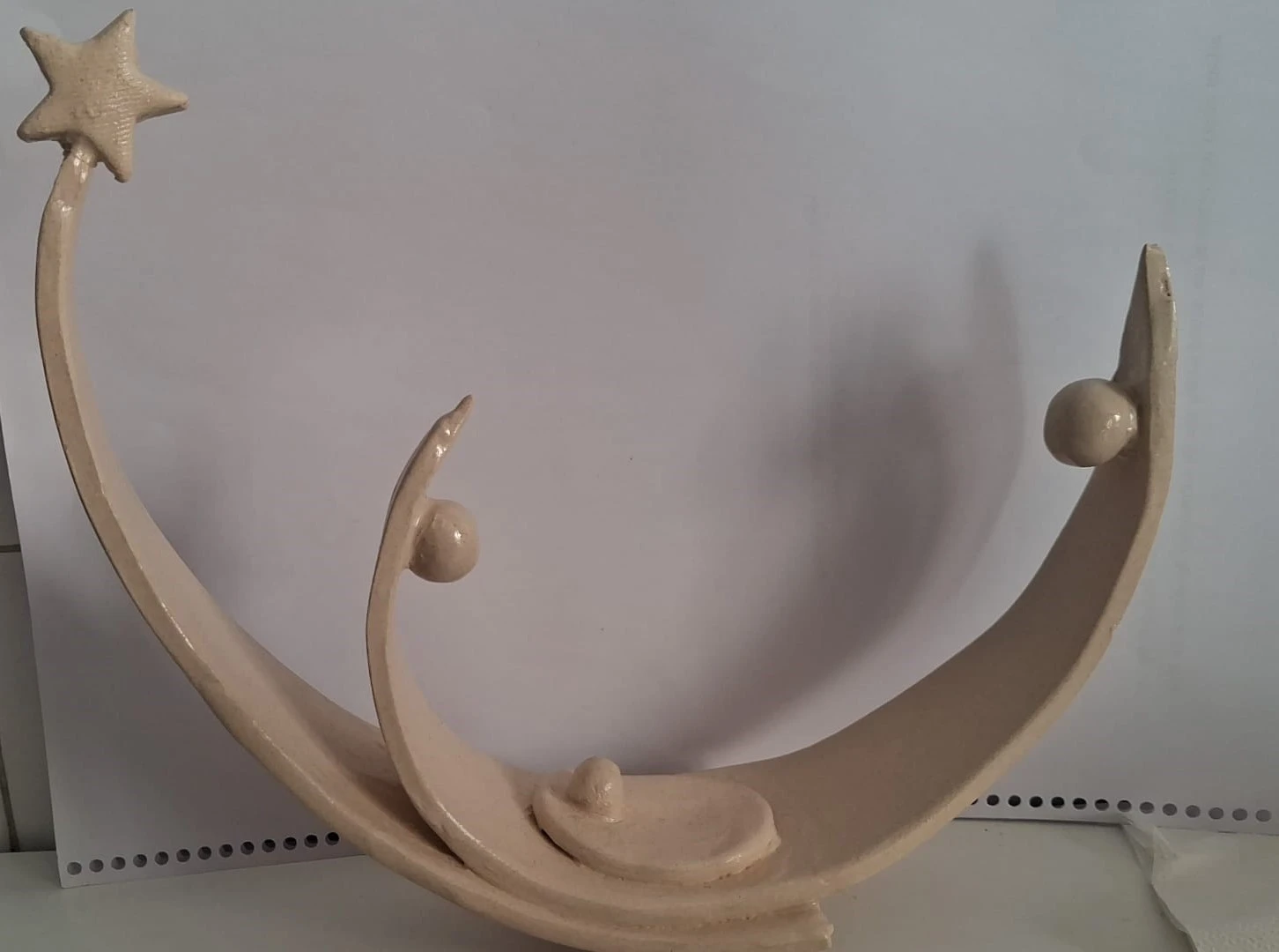 Belén de Navidad moderno de cerámica esmaltada en color crema, con formas curvas en media luna, tres figuras esféricas, el Niño en el centro y una estrella, hecho a mano en Valladolid — CreArte