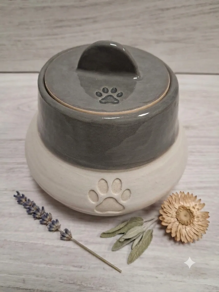 Bote de cerámica artesanal para chuches de mascota, con tapa esmaltada en gris y huella grabada, hecho a mano en Valladolid