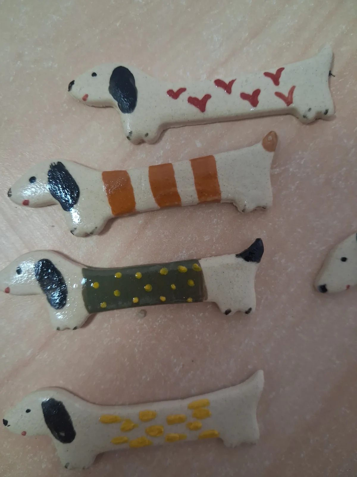 Colección de broches de cerámica con forma de perro salchicha crudos pintados a mano con corazones rojos, rayas naranjas, lunares amarillos sobre verde y lunares amarillos sobre crudo
