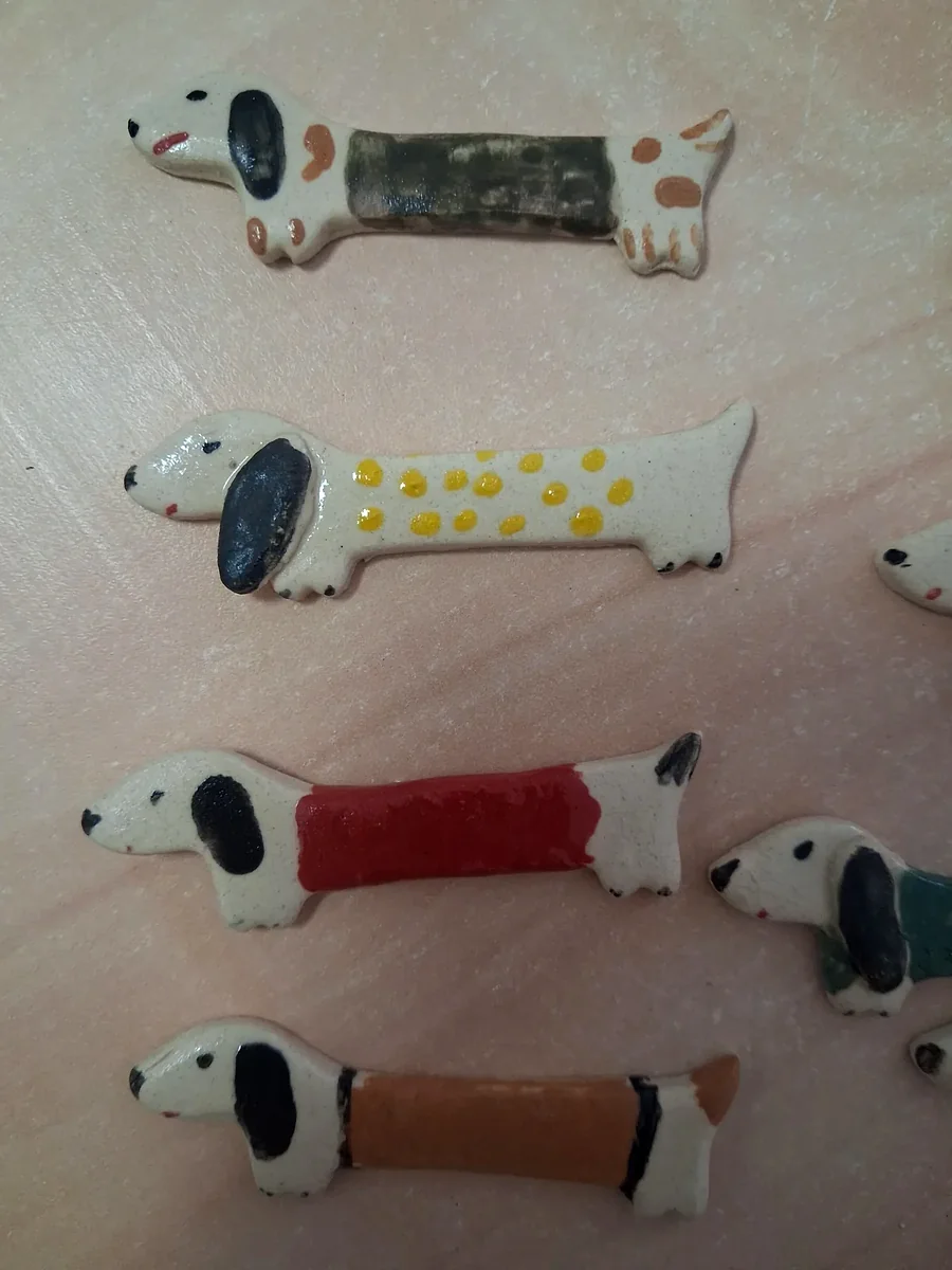 Colección de broches de cerámica con forma de perro salchicha crudos pintados a mano con manchas verdes y naranjas, lunares amarillos, rojo liso y rayas naranjas