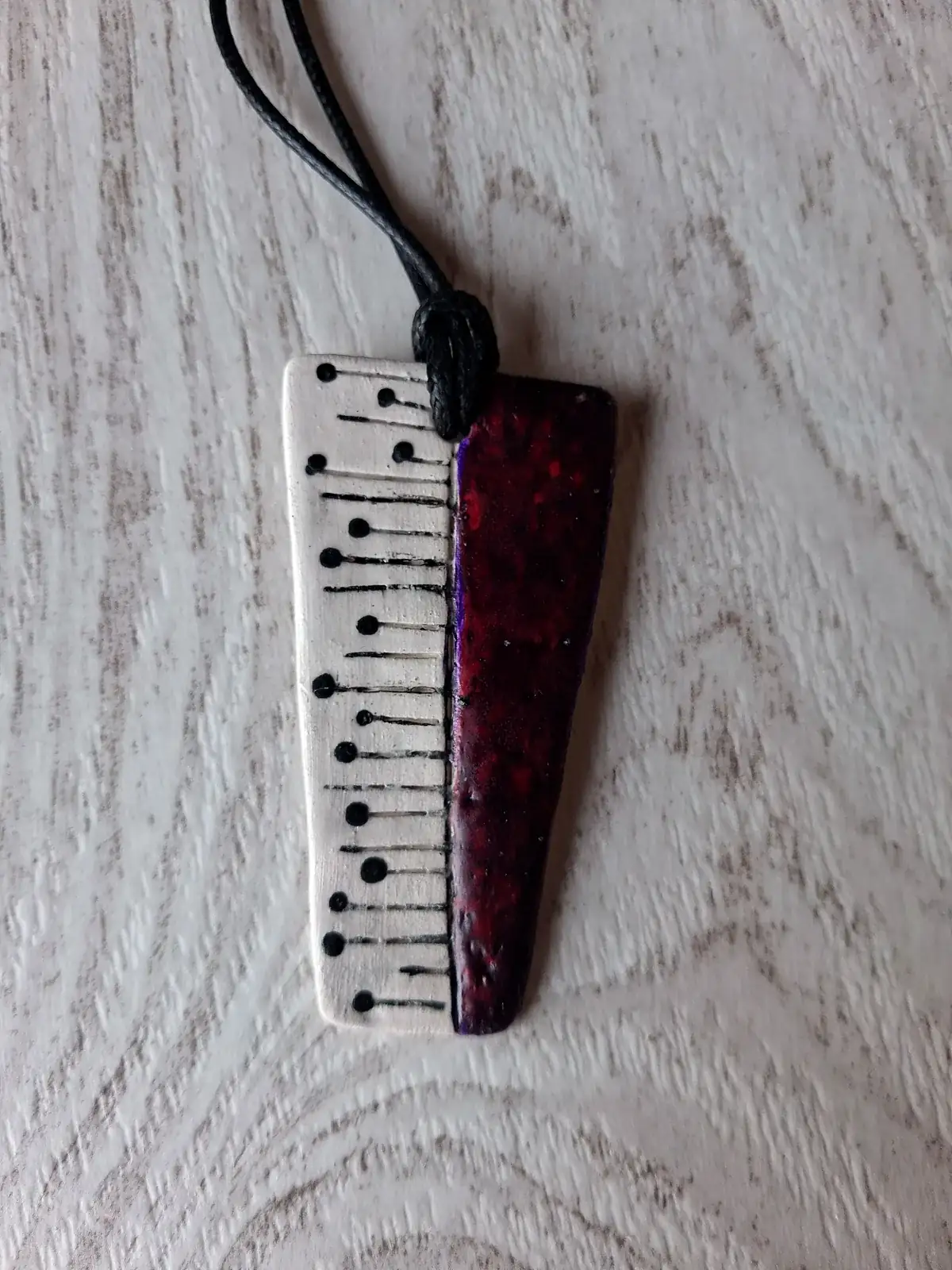Collar de cerámica artesanal rectangular en blanco y granate, con líneas negras rematadas en puntos y esmalte moteado