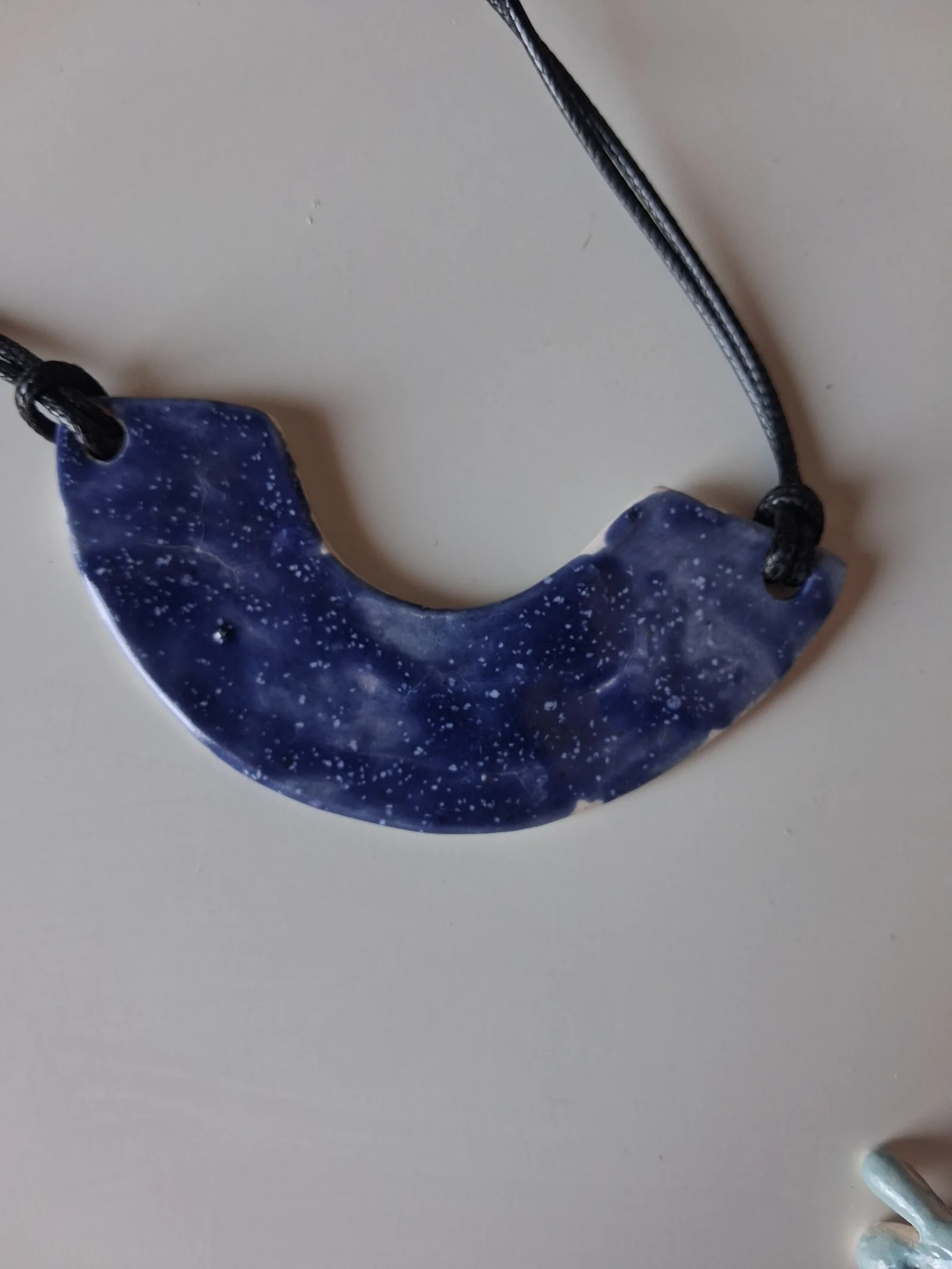 Collar de cerámica con textura en forma de media luna, esmalte azul moteado con pintas blancas