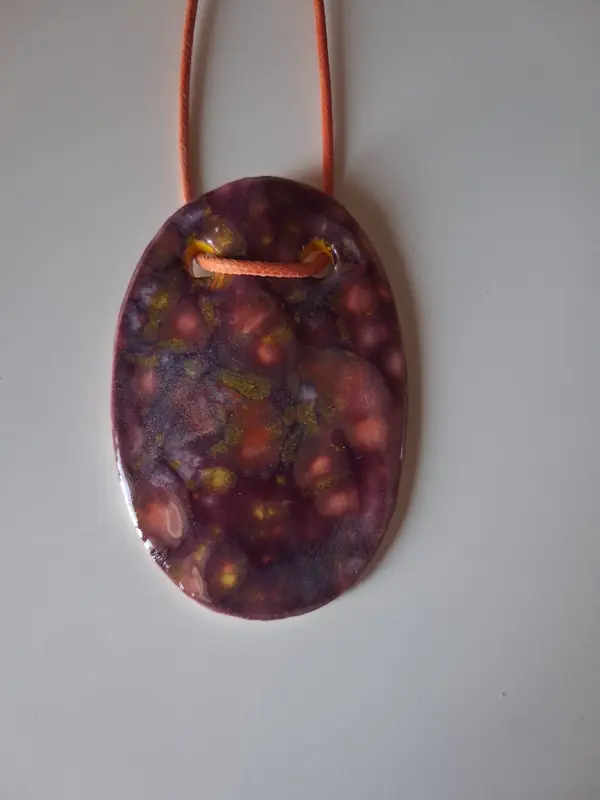 Collar de cerámica con textura de forma ovalada, esmalte morado y burdeos moteado, montado sobre cordón naranja