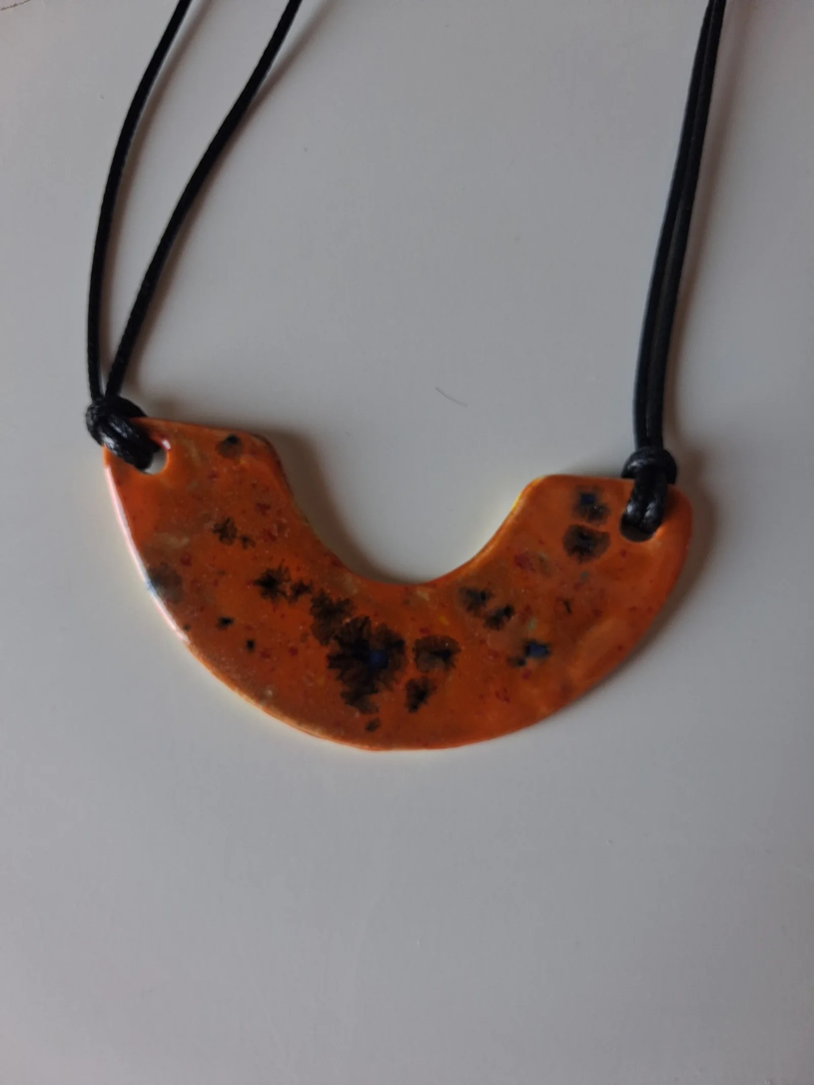 Collar de cerámica con textura en forma de media luna, esmalte naranja moteado con motas negras