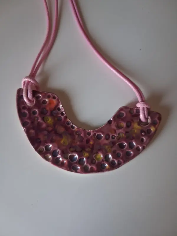 Collar de cerámica con textura en forma de media luna, esmalte rosa y burdeos moteado, montado sobre cordón rosa