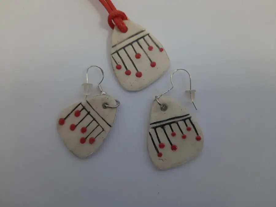 Conjunto artesanal de cerámica blanca con líneas negras y puntos rojos: collar y pendientes a juego, hecho a mano en taller CreArte Valladolid