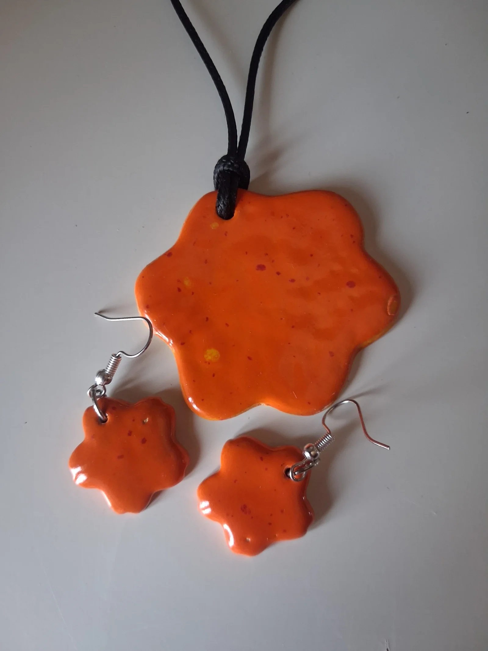 Conjunto artesanal de cerámica naranja con motas rojas y amarillas: collar y pendientes con forma de flor a juego, hecho a mano en taller CreArte Valladolid