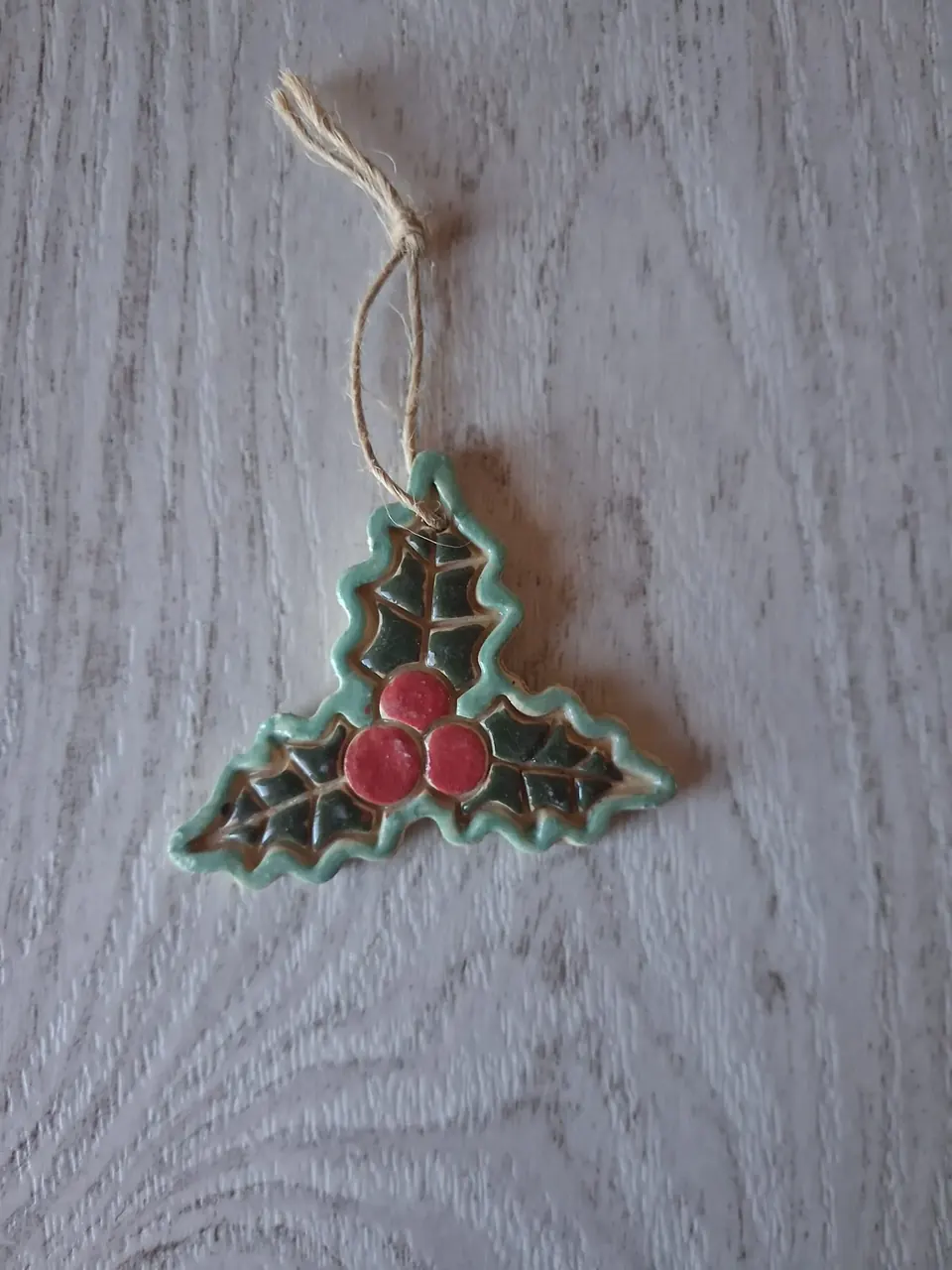 Figura de Navidad de cerámica con forma de hojas de acebo verde oscuro con borde turquesa y tres bayas rojas, con cordel de yute para colgar, de unos 5-6 cm, hecha a mano en Valladolid — CreArte