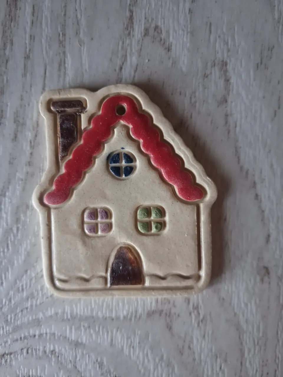 Figura de Navidad de cerámica con forma de casita beige con tejado rojo ondulado, chimenea marrón, ventanas de colores y puerta marrón, con agujero para colgar, de unos 5-6 cm, hecha a mano en Valladolid — CreArte