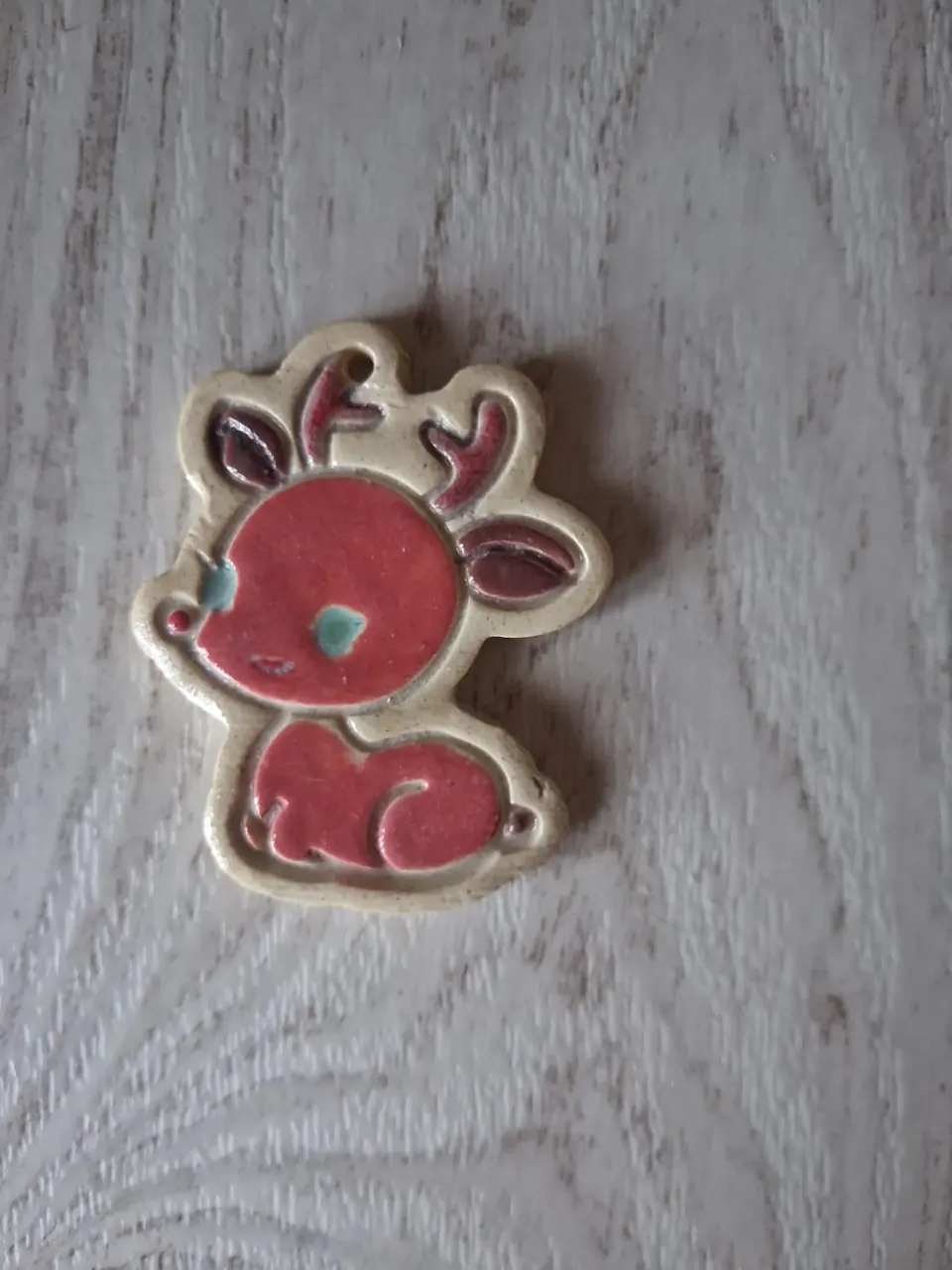 Figura de Navidad de cerámica con reno pequeño sentado, cuerpo rojo, orejas y cuernos granates y ojos turquesa, esmaltado a mano y con agujero para colgar, de unos 5-6 cm, hecha a mano en Valladolid — CreArte
