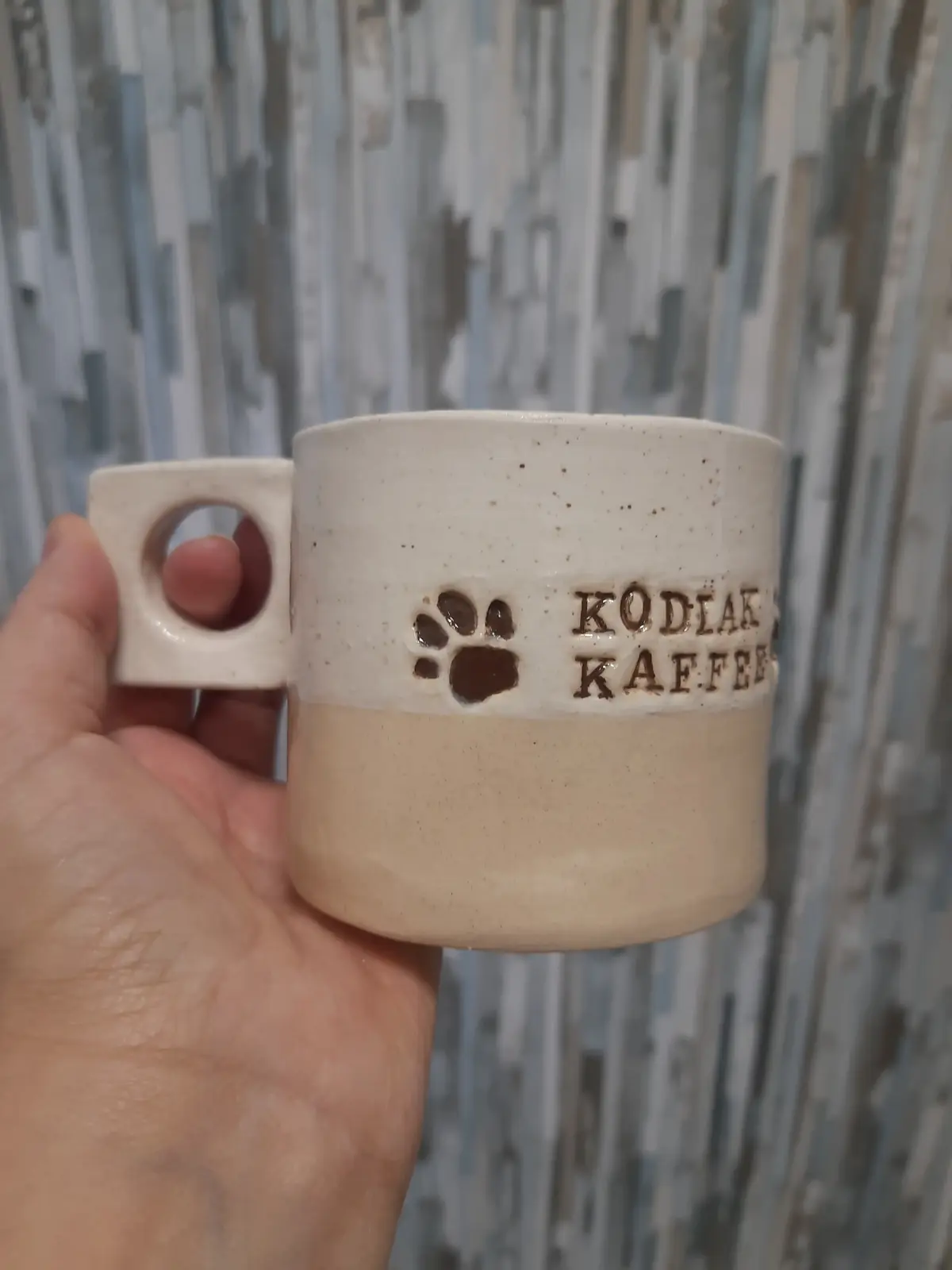 Taza de cerámica con asa cuadrada y estampado de huella y texto grabado, hecha en clases semanales de CreArte