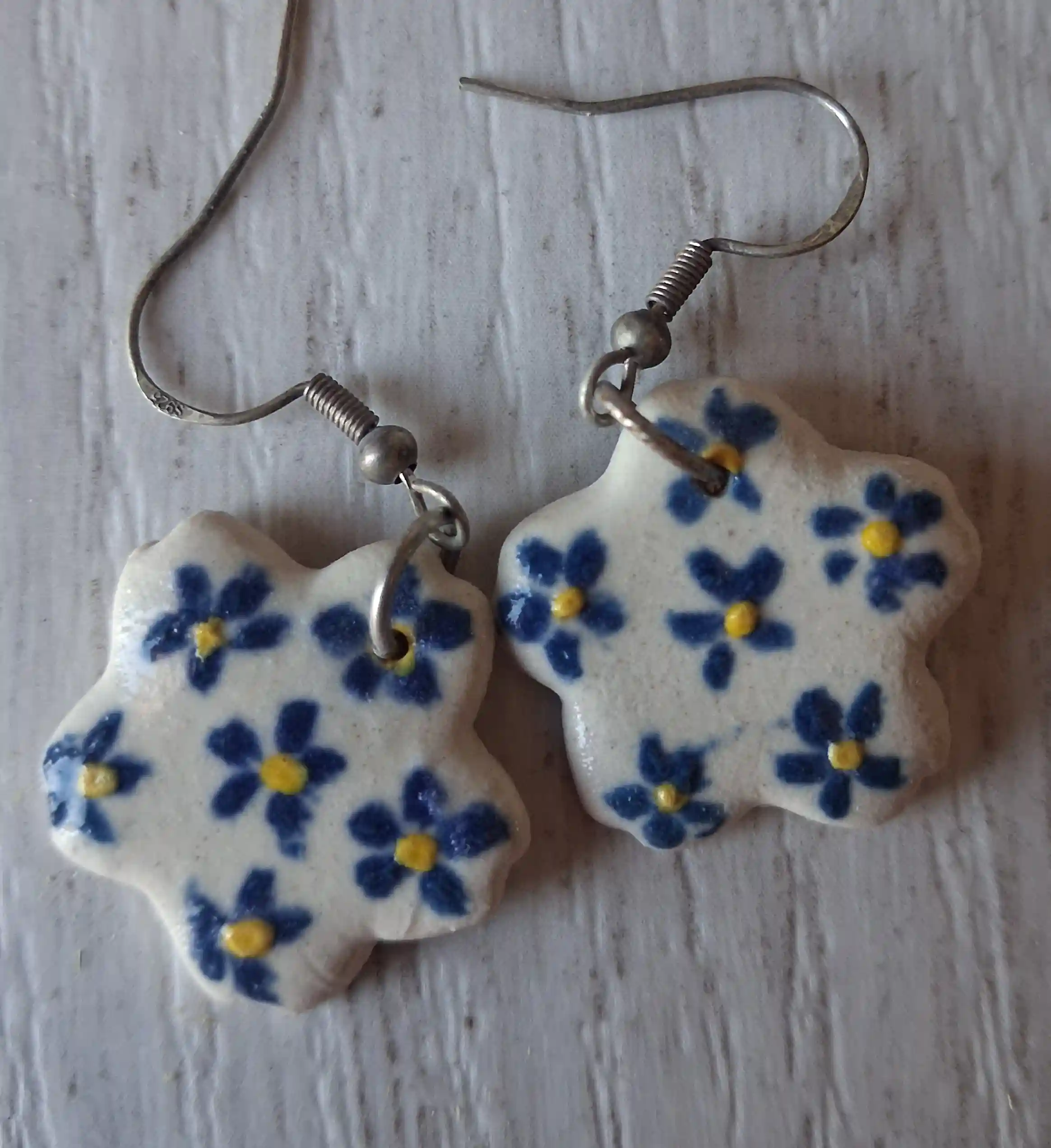 Pendientes de cerámica con forma de flor, fondo crema con florecillas azules pintadas a mano