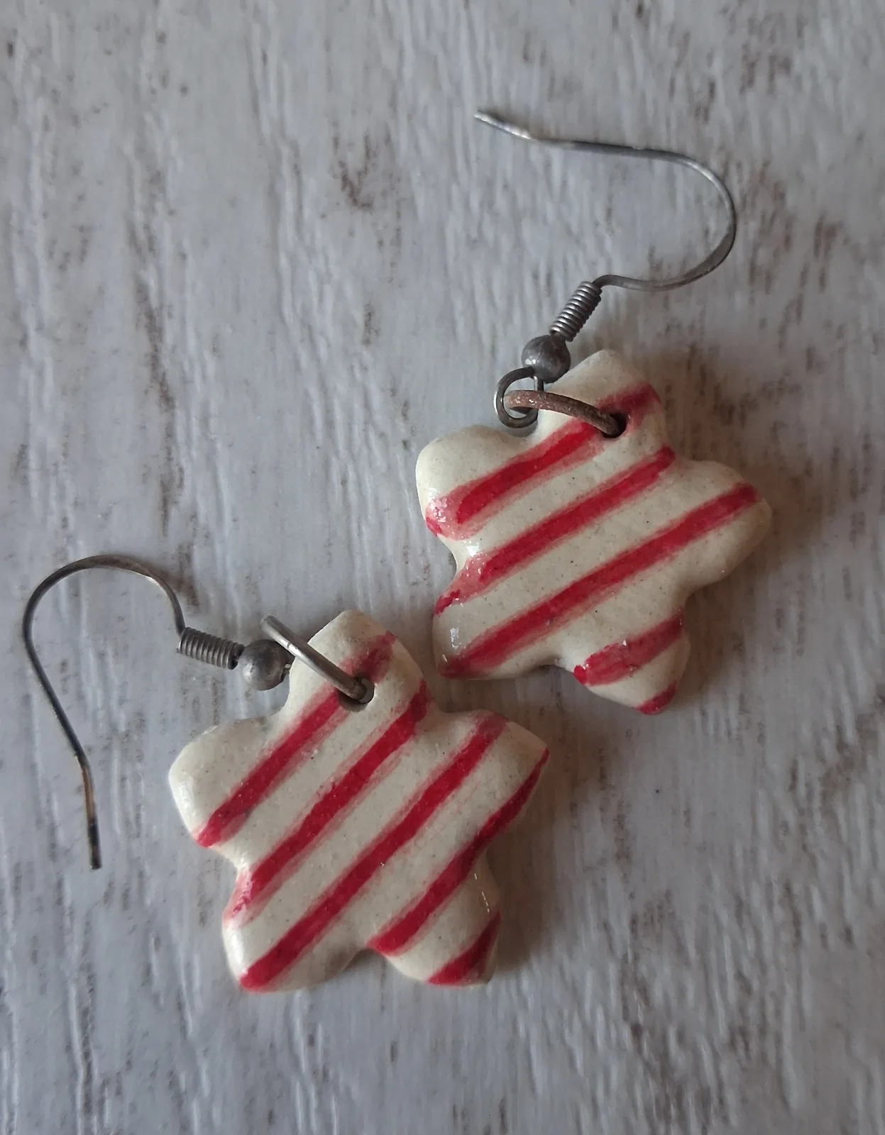 Pendientes de cerámica con forma de flor y rayas rojas sobre fondo crema