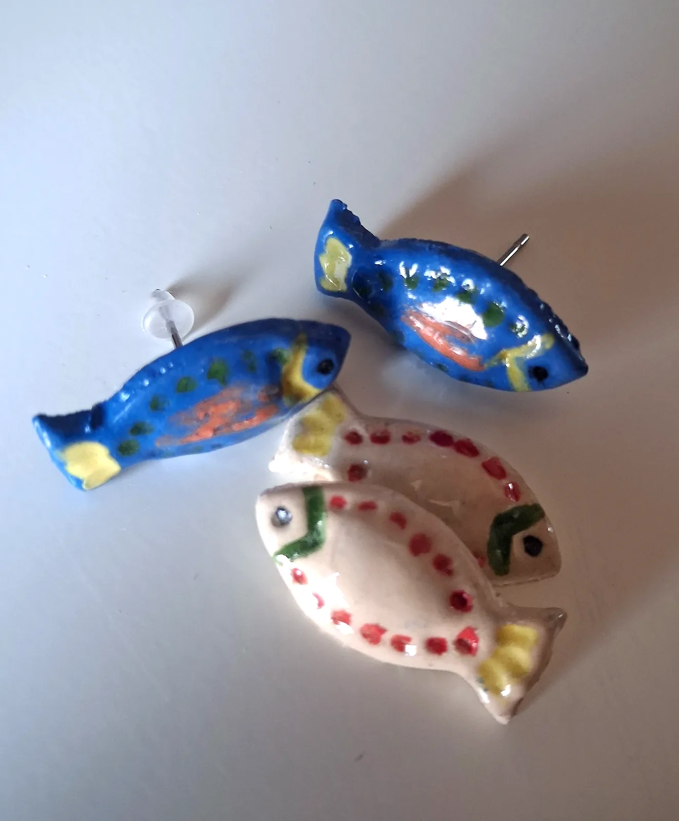 Pendientes de cerámica pequeños con forma de pez en azul y en crema con detalles pintados a mano