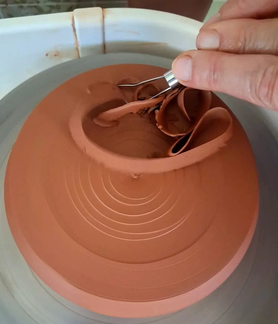 Pieza de barro rojo siendo retorneada en el torno alfarero — taller de cerámica CreArte Valladolid