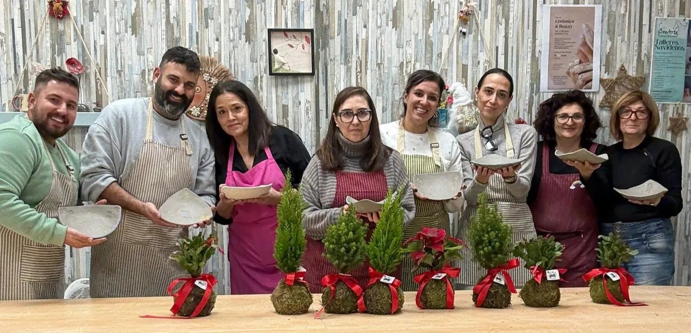 Grupo de alumnos sonriendo con sus kokedamas terminados en el taller de kokedama y cerámica de CreArte Valladolid