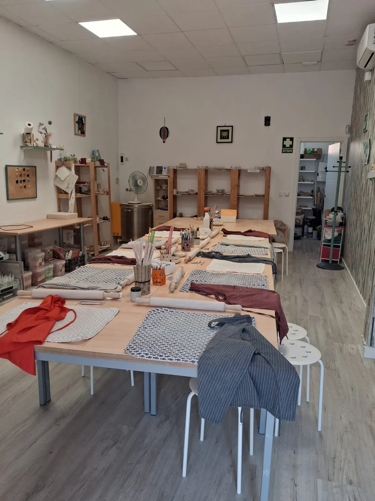 Mesa de taller de cerámica preparada con delantales, herramientas y rodillos para una clase en Valladolid